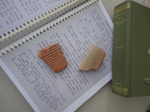 Two shards, roughly quadrilateral, one scored, diameter about a third the length of the spine of a Loeb volume