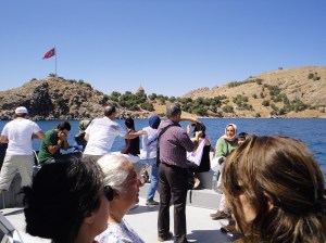 Many people stand on the prow of a boat;