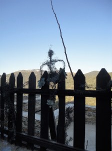 Human figure sculpted from wire climbing picket fence against sunlit hillside opposite, Şirince, January, 2018