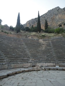 Rows of seats of an ancient theater, with cypresses and a mountain above