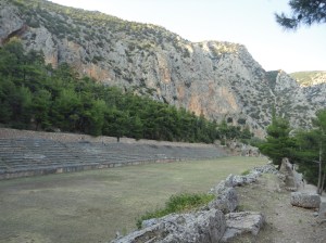 Ancient stadium among trees, cliffs behind