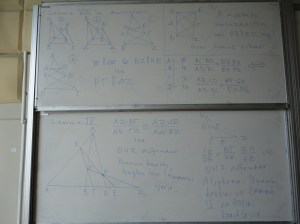 Two whiteboards, one above the other, with geometrical diagrams and equations