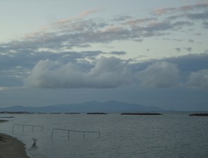 Mountain beyond sea, two layers of clouds above