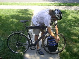 Bicycle with rider next to it, leaning over to the front panniers