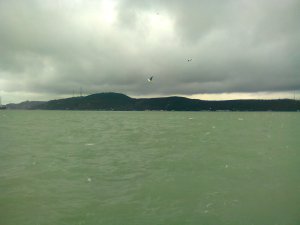 Hills of the Asian shore form a dark line between an olive-drab Bosphorus and the leaden clouds above