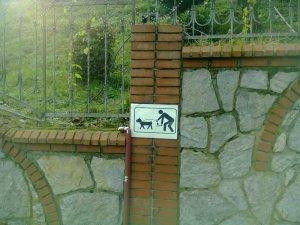 Sign: Dog marching in front; human behind, bent over, scooping