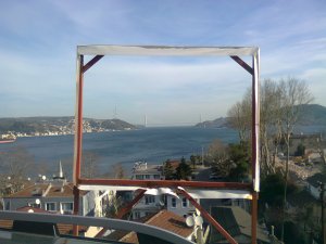 A distant bridge between continents, seen through the frame from which a poster has been cut out