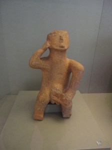 Terra cotta figure gazing upward, holding right hand to head, left hand to penis (now broken off)