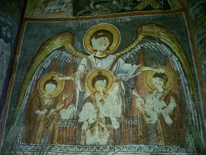 Three haloed figures in front of a fourth with spread arms and wings; faces are mostly scratched out