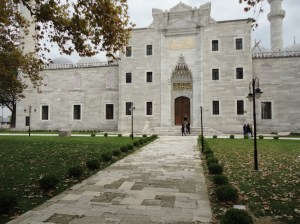 Stone walkway between lawns leads to narrow gateway in stone building