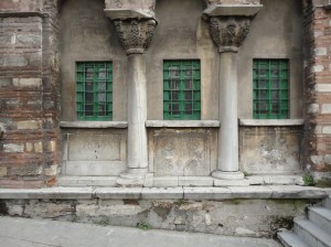In a wall, three rectangular windows separated by two columns with broad capitals