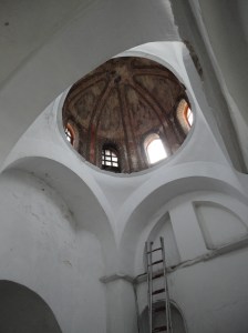 Above whitewashed supports, an old dome with windows at base shows faded remains of decoration