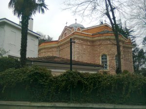 Church of red brick from below and the other side of a wall covered with ivy