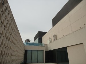 Beyond dark and light walls, a higher terrace, with furled umbrellas and a potted tree, and then the sky